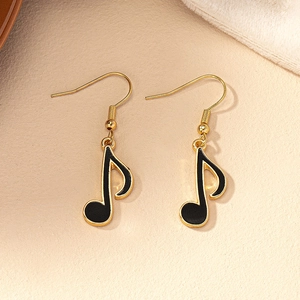 Macro detail of music note earrings with gold metal outlines and black enamel finish