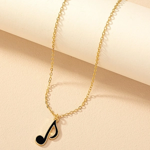 Détail d'un pendentif note de musique avec bords dorés et émail noir sur chaîne fine