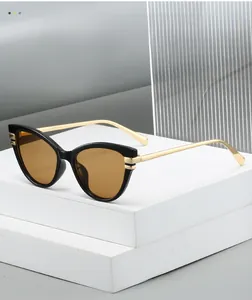 Close-up of retro cat-eye sunglasses with black frame, gold temples and brown lenses
