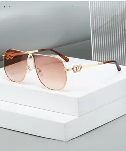 Detail of gold aviator sunglasses with dual-heart cutout temple and gradient brown lenses