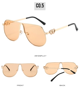 Detail view of gold aviator sunglasses with hollow heart-shaped temples and orange lenses