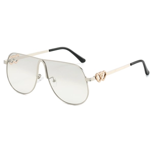 Oversized silver pilot sunglasses with gold double-heart hinge detail on white background