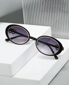 Detail of oval sunglasses with golden edge, gradient purple lenses and red heart accents