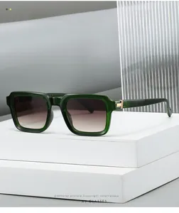 Detail of square olive green frame sunglasses with gradient lenses and gold metal hinges