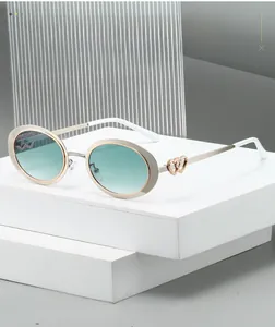 Detail of oval frame sunglasses featuring gradient lenses and double heart metal temples