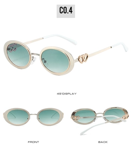 Detail view of oval sunglasses with gold frames and double heart accents on temples