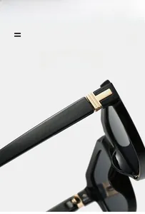 Detail of square black sunglasses with iconic gold metal hinge and high-end finish
