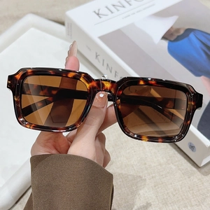 Classic retro square sunglasses with tortoiseshell frames and brown lenses held by hand