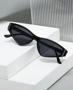 Détail de lunettes de soleil œil-de-chat noires 2025 avec accents métalliques sur socle blanc