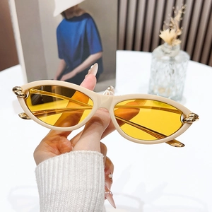 Chic cat-eye sunglasses with beige frames, yellow lenses and gold chain link details