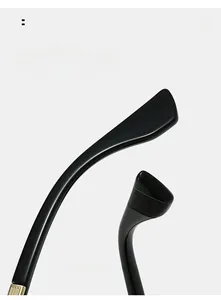 Detail of curved black spectacle legs with anti-slip texture and gold metal trim
