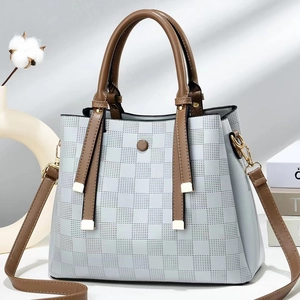 Detail of checkered embossed texture and brown decorative buckle on dual-tone handbag