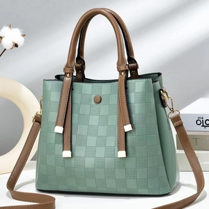 Detail of mint green checkered texture handbag with brown straps and gold hardware