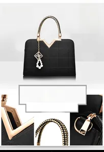 Detail of black textured handbag with golden V-trim and pearl woven handle