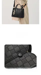 Close-up of black leather bag featuring woven texture and gold leaf pendant detail