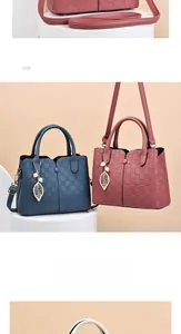 Detail of plaid embossed handbag with elegant leaf metal pendant and pearl charm accessory