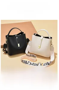 Detail of lychee pattern leather bucket bags with wide logo straps and gold hardware