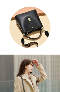 Detail of black pebbled leather bucket bag with gold buckle and jacquard shoulder strap