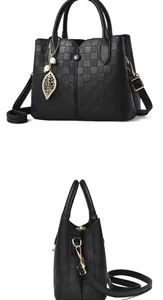 Detailed view of black litchi leather handbag featuring woven texture and gold pearl charm