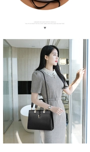 Detail of elegant black woven tote bag with gold hardware worn by a model in interior