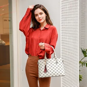 White geometric printed tote bag with tassels carried by a model in casual wear