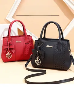 Détail de sacs à main en cuir litchi rouge et noir avec nœud et breloque cœur