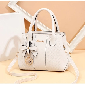 Détail du sac à main blanc en cuir matelassé avec logo métallique et nœud décoratif
