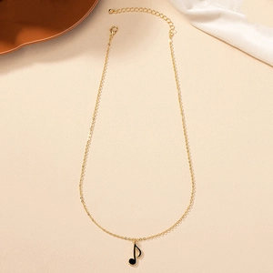 Collier avec pendentif note de musique dorée sur tissu en soie et fond texturé