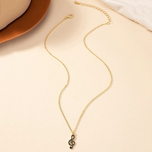 Détail du collier pendentif clé de sol avec émail noir et chaîne dorée élégante