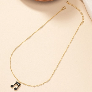 Détail d'un pendentif note de musique dorée en émail noir avec chaîne ajustable
