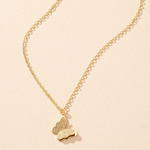Detailed close-up of golden butterfly pendant with frosted texture on fine link chain