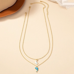 Vue rapprochée de deux colliers dauphins dorés avec pendentifs blanc et bleu scintillant