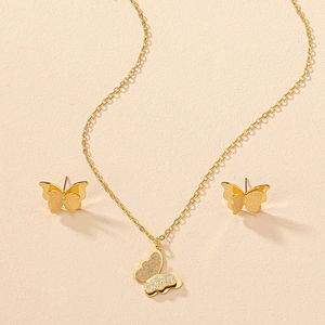 Macro view of golden butterfly necklace and earrings set with matte shimmering texture