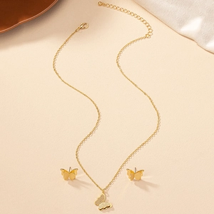 Elegant gold butterfly jewelry set with necklace and stud earrings on soft fabric