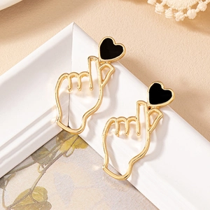 Gros plan de boucles d'oreilles cœur doré avec émail noir sur un cadre décoratif blanc