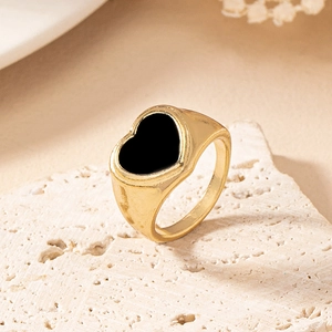 Detail shot of heart enamel ring with gold finish on white textured stone background