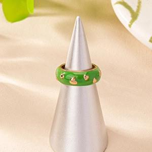 Bague en émail vert avec cœurs dorés sur un support de présentation conique gris