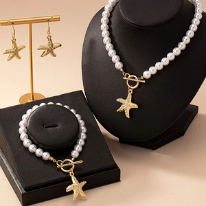 Elegant gold starfish pearl jewelry set with necklace bracelet and earrings on velvet stand