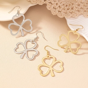 Macro detail of gold and silver hollow heart-shaped clover drop earrings on lace