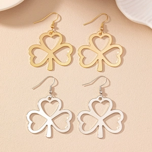 Minimalist gold and silver shamrock earrings with hollow heart details on warm background