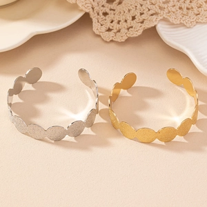 Detail of matte gold and silver open bangles featuring textured oval link design