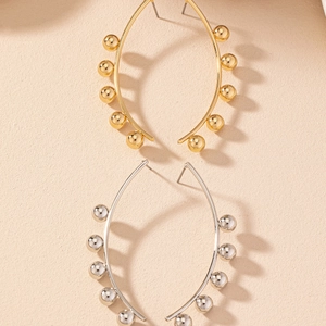 Dettaglio di grandi orecchini a cerchio oro e argento con piccole perline metalliche