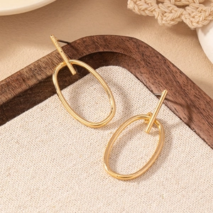 Minimalist gold oval geometric earrings with T-bar pins displayed on a wooden tray