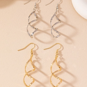 Détails macro des boucles d'oreilles spirales dorées et argentées sur support céramique