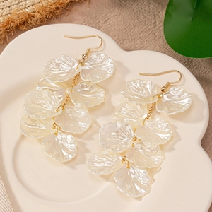 Elegant white shell flower tassel earrings with gold hooks on a ceramic plate