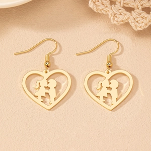 Détail de boucles d'oreilles cœur dorées avec silhouettes romantiques d'un baiser