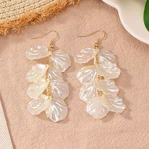 Detailed view of elegant shell flower tassel earrings on textured beige fabric