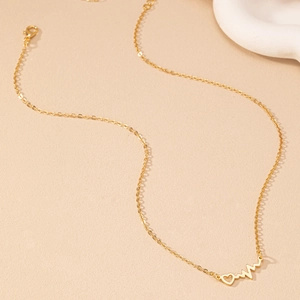 Collier élégant cœur doré avec ligne de pulsation et pendentif sur fond beige doux