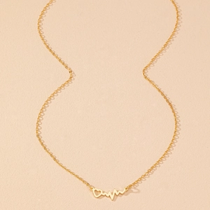 Détail du collier doré battement de coeur avec pendentif ajouré sur fond texturé
