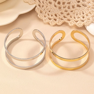 Detail showing gold and silver geometric open bangles on beige textured backdrop